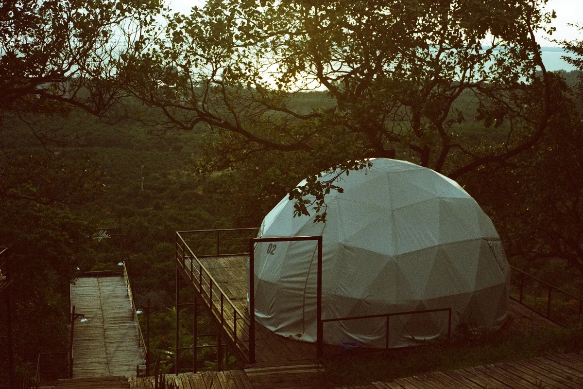 Doğa manzarasına bakan ahşap teras üzerinde kubbe (geodome) glamping çadırı
