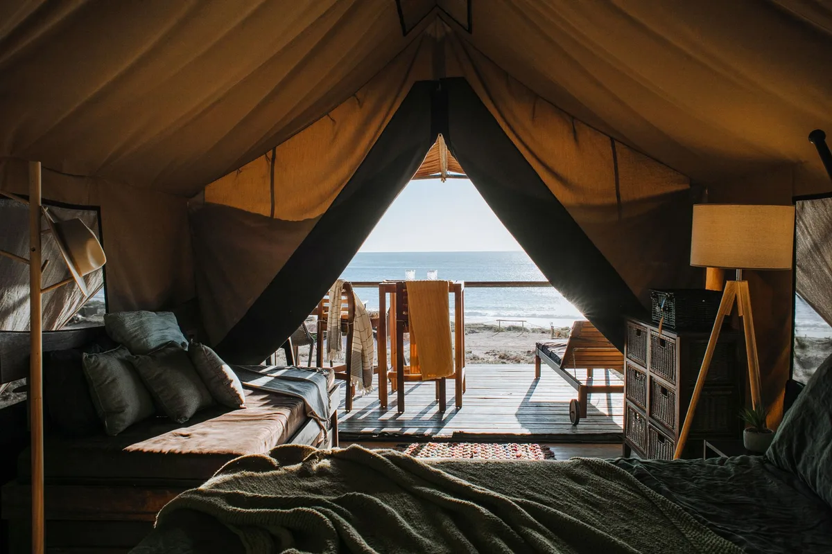 Glamping çadırının içi: gerçek yatak, yastıklar ve açık kapıdan görünen manzara